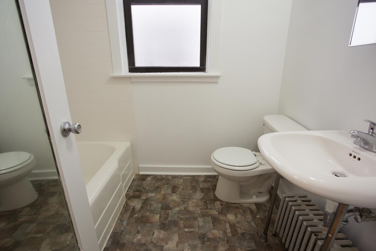 A bathroom with a toilet, sink, and a window.