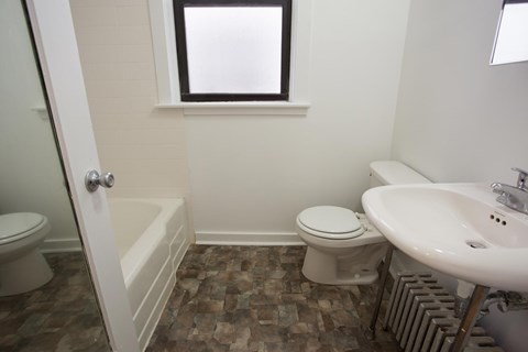 A bathroom with a toilet, sink, and a window.
