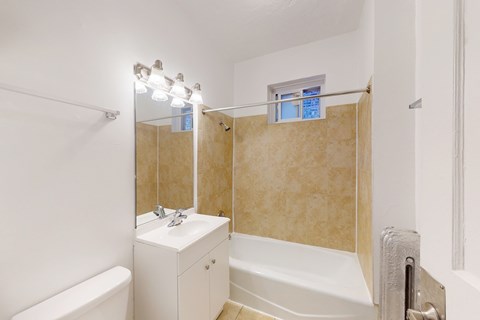A white bathroom with a tub, sink, and mirror.