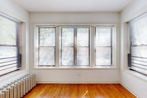 A room with a wood floor and three windows.