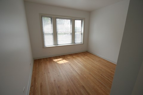 A room with a window and wooden flooring.