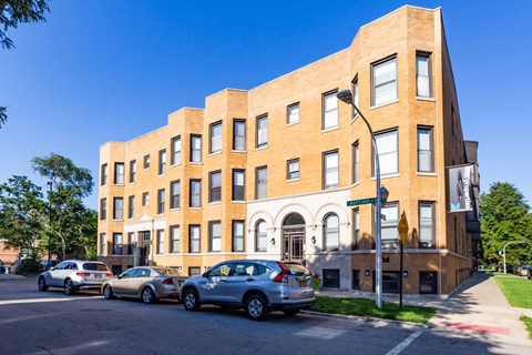A street view of a building with cars parked in front.