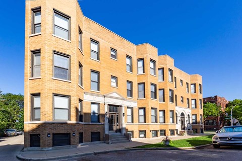 A large brick building with many windows and a car parked in front.