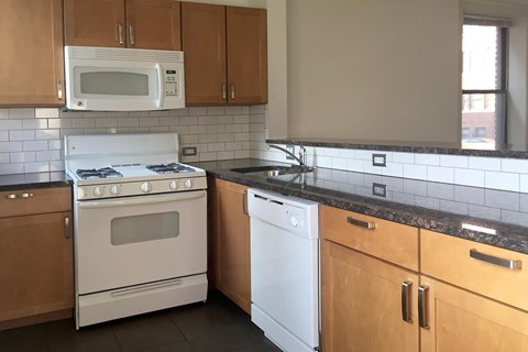 A kitchen with a white stove top oven and a white dishwasher.