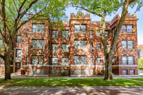 A red brick building with trees in front.