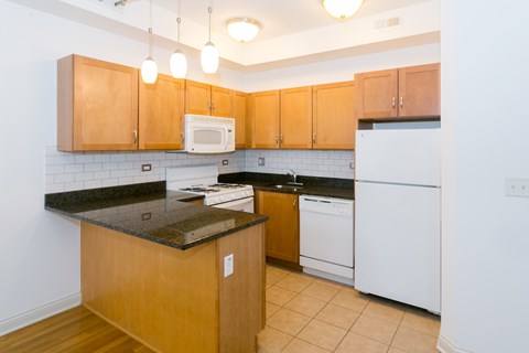 A kitchen with wooden cabinets and black countertops.