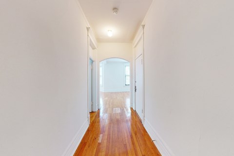 A long hallway with wooden floors and white walls.