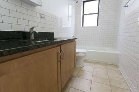 A bathroom with a black granite countertop and a white toilet.