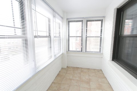 A room with a tiled floor and a window with blinds.