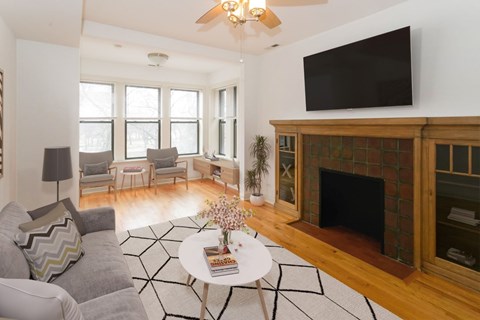 A living room with a fireplace and a television mounted above it.