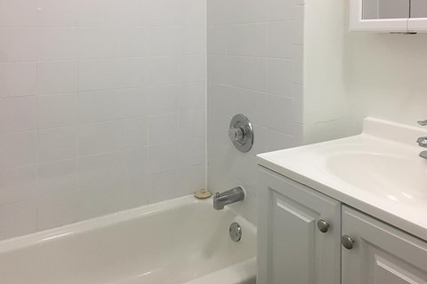 A white bathroom with a tub and sink.