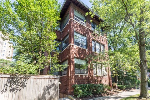 A red brick building with a tree in front.