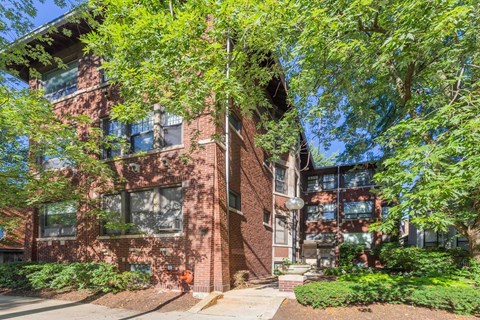 A red brick building with trees in front.