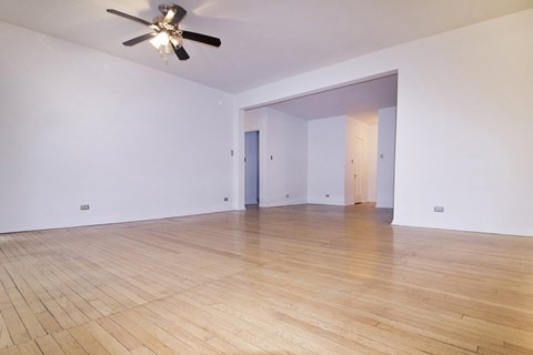A room with a ceiling fan and wooden flooring.