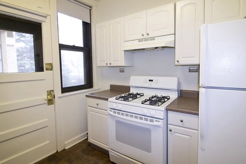 A white kitchen with a stove and a refrigerator.