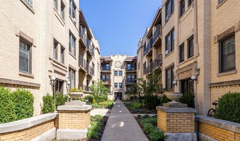 A sunny day in a quiet residential area with a pathway between two rows of apartment buildings.