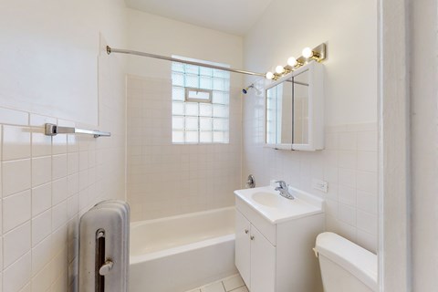 A white bathroom with a tub, sink, and mirror.