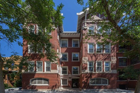 A red brick building with a tree in front.