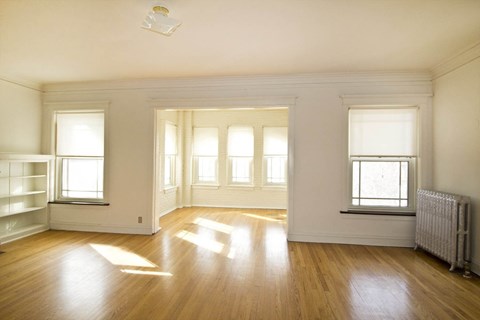 A sunny room with wooden floors and white walls.