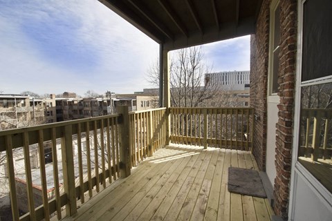 A wooden deck with a view of a parking lot and buildings.