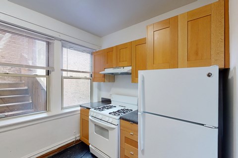 A kitchen with a white fridge, stove and wooden cabinets.
