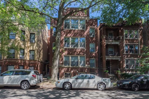 Three cars are parked in front of a red brick building.