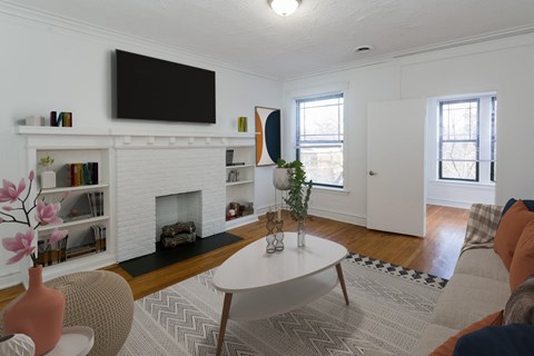A living room with a fireplace and a television mounted above it.