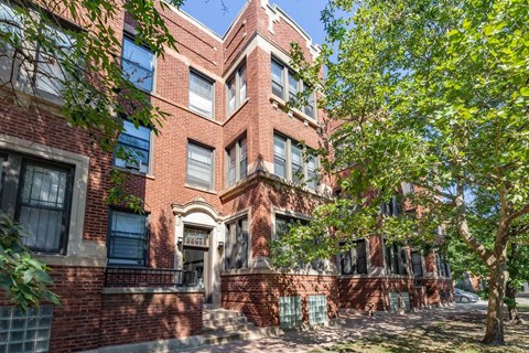 A red brick building with a tree in front.