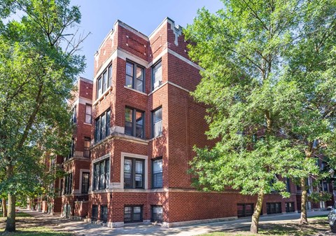 A red brick building with trees in front.