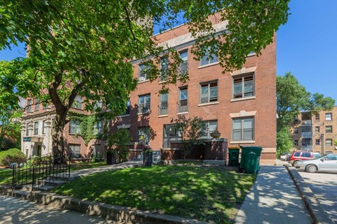 A red brick building with a green tree in front.