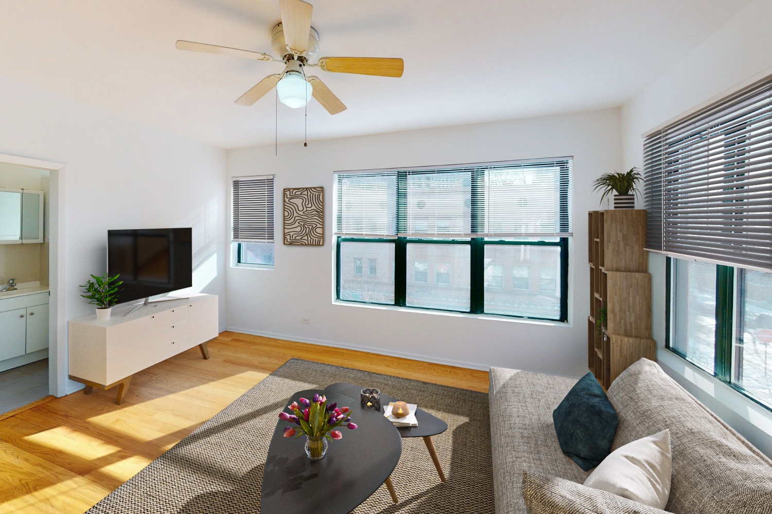 A living room with a grey sofa, a coffee table, a television, and a ceiling fan.