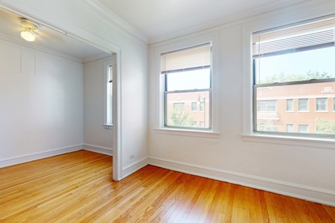 A room with wooden floors and two windows.