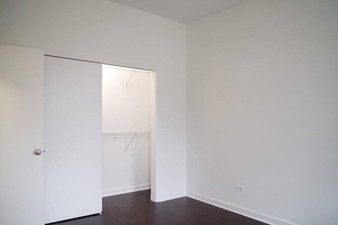 A white door is open to a room with white walls and a wooden floor.