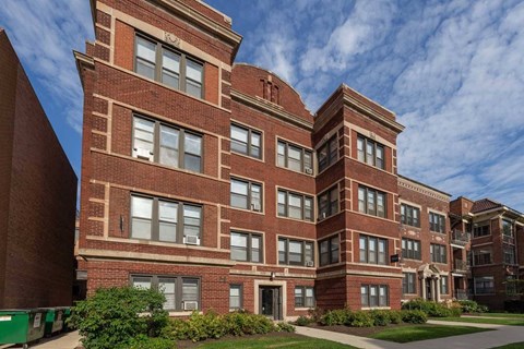 A large red brick building with a green lawn in front.