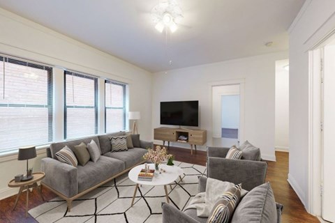 A living room with a grey couch, a white coffee table, and a flat screen TV.