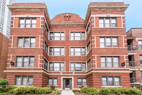 A red brick building with a symmetrical facade and a balcony on the top floor.