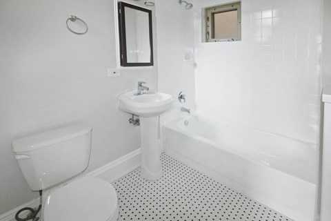 A white bathroom with a toilet, sink, and bathtub.