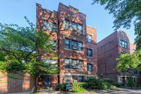 A red brick building with trees in front.