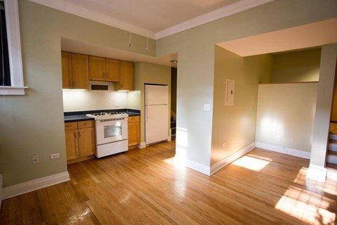 A kitchen with wooden floors and a white refrigerator.