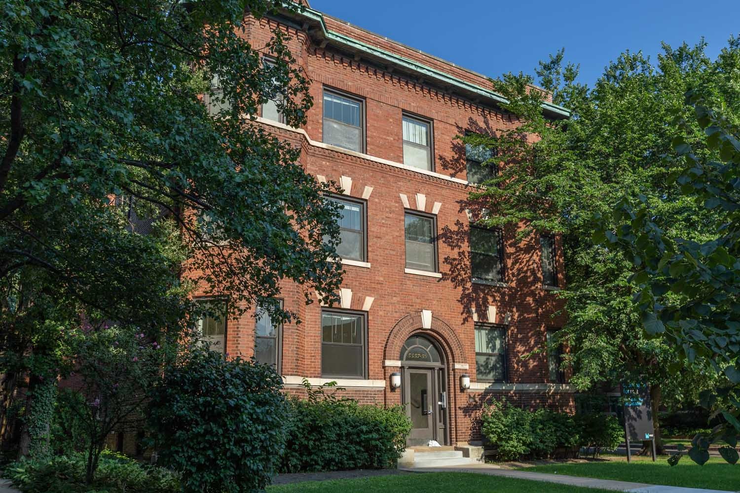A red brick building with a green lawn in front.