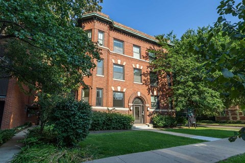 A red brick building with a green lawn in front.