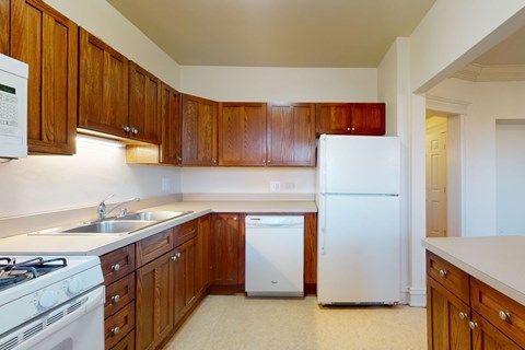 A kitchen with white appliances and wooden cabinets.