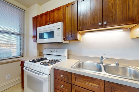 A kitchen with a white stove, a white microwave, and a white sink.