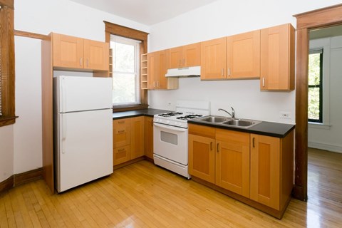 A kitchen with wooden cabinets and a white fridge.