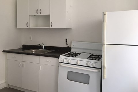 A white refrigerator stands next to a stove in a kitchen.
