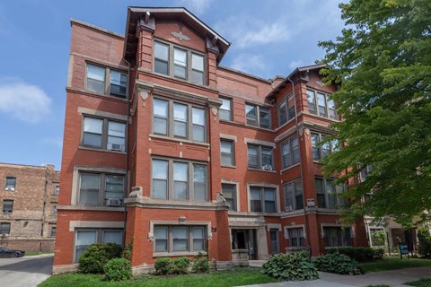 A red brick building with a green lawn in front.