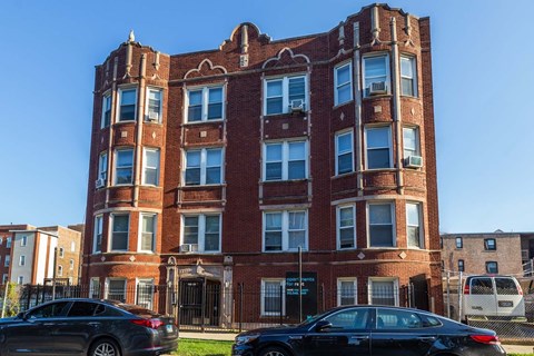 A red brick building with a black car parked in front.