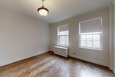 A room with wooden flooring and a window with blinds.