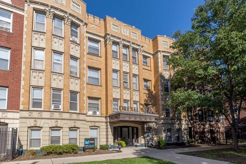 A large, multi-story building with a brick facade and a green lawn in front.