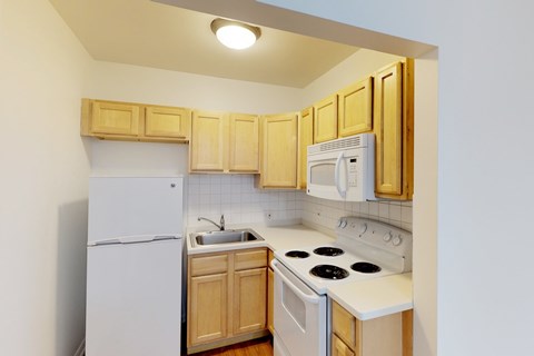 A kitchen with white appliances and wooden cabinets.